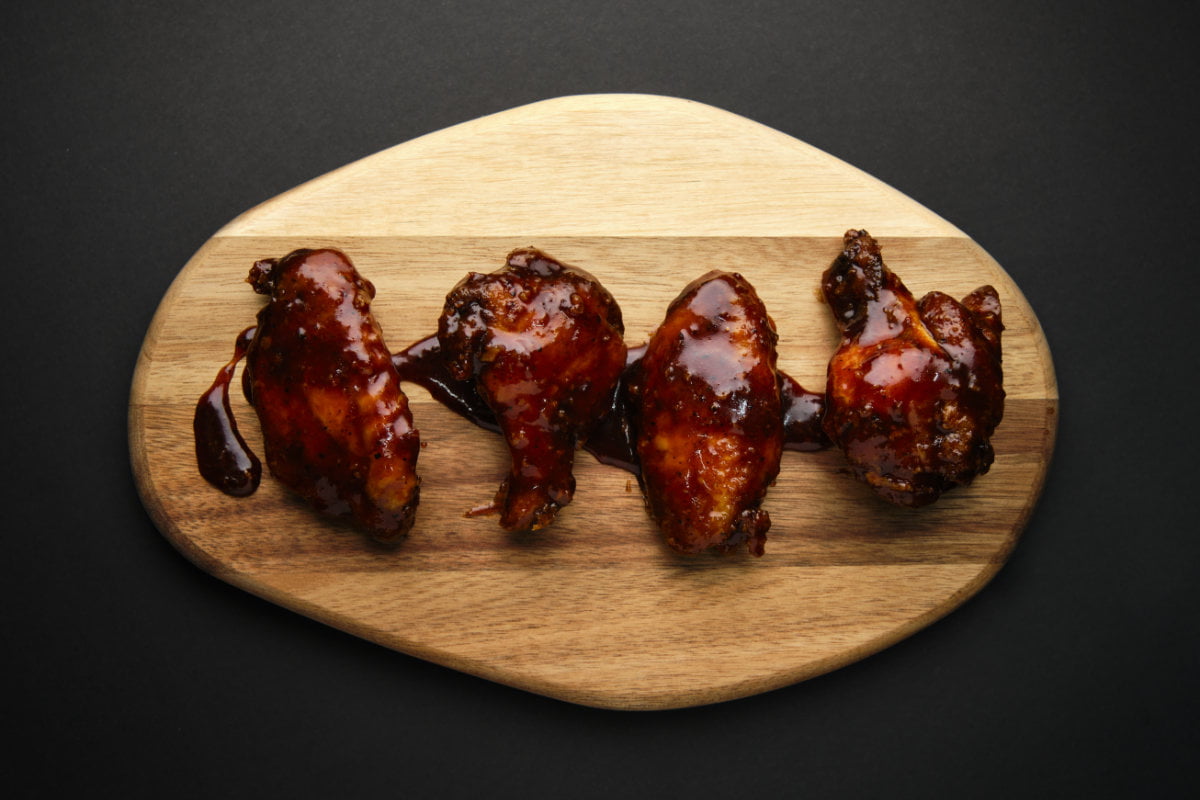 Alitas de pollo sobre tabla de madera en mesa oscura